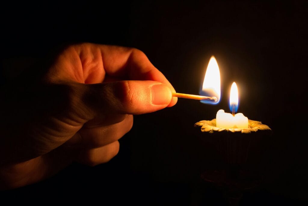 Lit match lighting a candle in the dark.